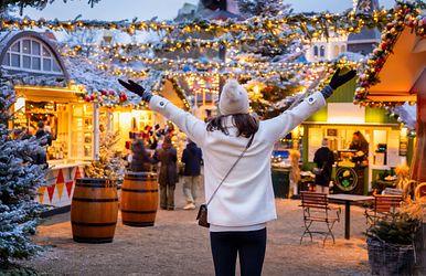 Eine Frau besucht schneebedeckten Weihnachtsmarkt