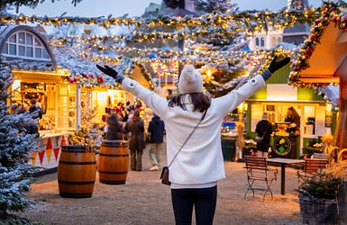 Eine Frau besucht schneebedeckten Weihnachtsmarkt