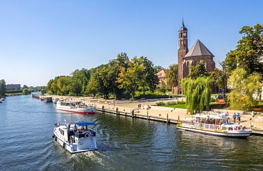 kleine Schiffe auf einem Fluss an einer Uferpromenade