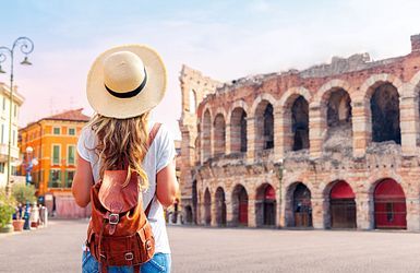 Frau mit Sonnenhut blickt auf antikes Amphitheater